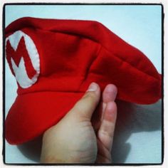 a hand holding a red hat with white letters on it