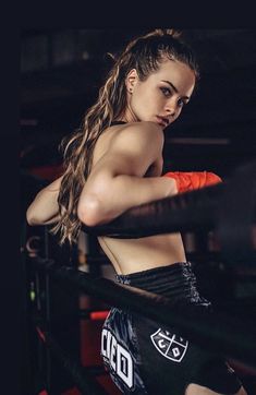 a beautiful young woman standing next to a boxing ring