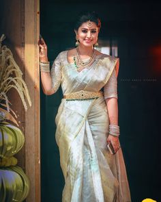 a woman wearing a white sari and gold jewelry