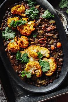 cauliflower and beans in a black dish with cilantro