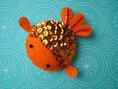 an orange fish with gold sequins on it's head