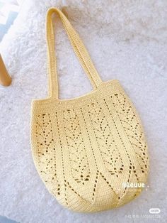 a crocheted yellow bag sitting on top of a white rug next to a wooden chair