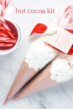 candy canes and marshmallows are wrapped in paper to make a hot cocoa kit