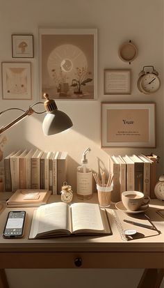 an open book sitting on top of a wooden desk next to a phone and lamp