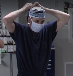 a man wearing a surgical mask and scrubs his head