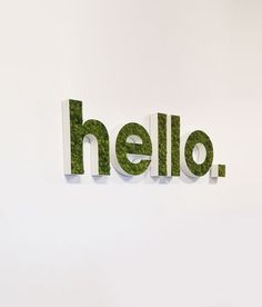 the word hello spelled with green grass in front of a white wall