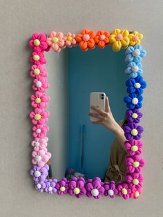 a woman taking a selfie in front of a mirror with flowers on the frame