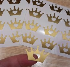 a hand is holding some gold crown stickers