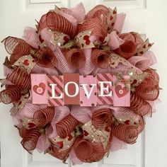 a pink and red wreath with the word love written in large letters on it's front door