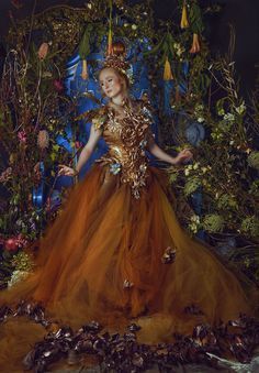 a woman in an orange dress surrounded by flowers