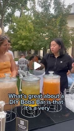 two women are talking to each other at an outdoor event with drinks on the table