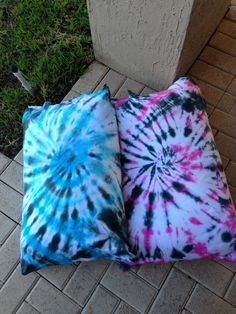 two pillows sitting on the ground next to a cement block with grass in the background