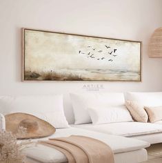 a living room with white furniture and a large painting on the wall over the couch