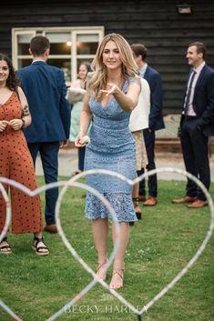 a woman in a blue dress standing on top of a lush green field next to other people