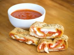 two pieces of bread with cheese and tomato on them next to a bowl of sauce