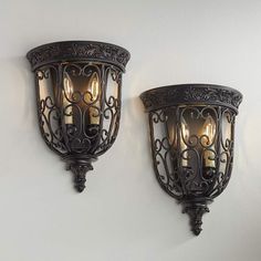 two wall lights mounted to the side of a white wall with ornate designs on it