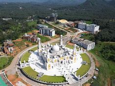 an aerial view of a large white building in the middle of a lush green area