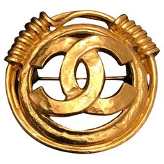 This vintage Chanel gold toned brooch is crafted of gold plated metal featuring a CC logo surrounded by a gold toned coiled ring. Stamped 94P made in France. Measures approximately 3.6 cm in diameter. Comes with box. Condition: Excellent vintage condition with minimal signs of wear Vintage Gold Brooches With Cabochon, Vintage Cameo Brooch In Yellow Gold, Chanel 1932 Fine Jewelry, Chanel Vintage, Vintage Gold-tone Jewelry Brooch, Vintage Yellow Gold Multi-stone Brooches, Vintage Chanel, Gold Tones, Chanel