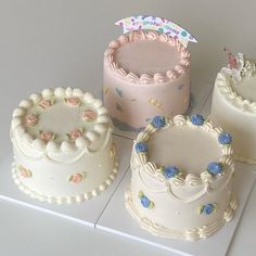 there are four different cakes on the counter top, each decorated with flowers and icing