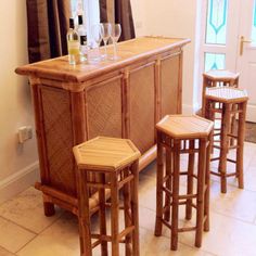 three wooden stools sitting next to a bar with wine glasses on top of it