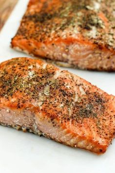 two pieces of salmon with seasoning on them