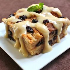 a white plate topped with blueberry bread pudding covered in icing and drizzled