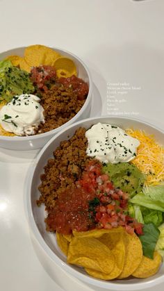 two bowls filled with different types of food on top of a white tablecloth covered table