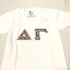 a white t - shirt with the letters af printed in pink, blue and green