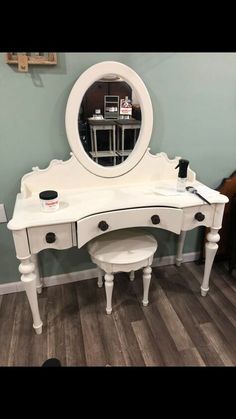 a white vanity table with two stools and a round mirror