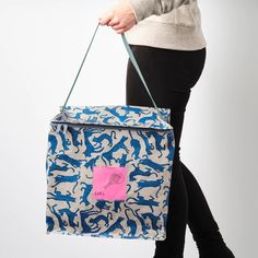 a woman carrying a blue and white tote bag with pink sticker on it