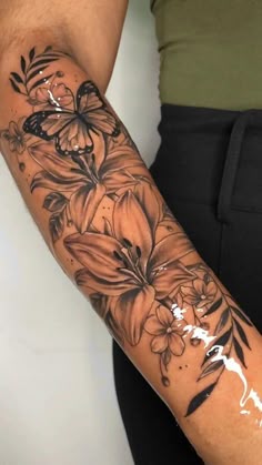 a woman's arm with flowers and butterflies tattooed on the side of her arm