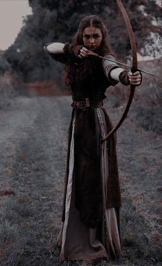 a woman dressed in brown holding a bow and arrow