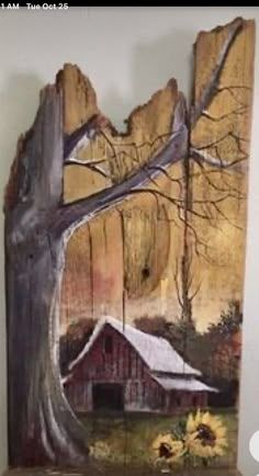 a piece of wood with a barn and sunflowers painted on it, in front of a white wall