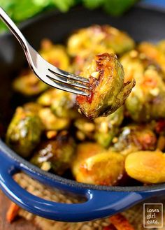 a fork full of brussel sprouts on a blue dish with other vegetables in the background