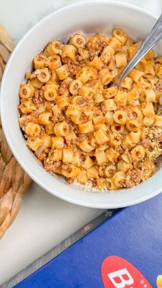 a white bowl filled with macaroni and cheese next to some breadsticks