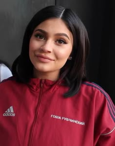 a woman in a red adidas jacket posing for the camera