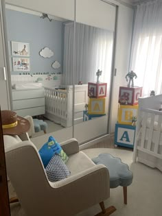 a baby's room with a crib, rocking chair and large mirror on the wall