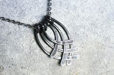 a black necklace with four pieces of metal hanging from it's center on a chain