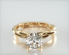 a yellow gold engagement ring with a round cut diamond in the center, on a white background