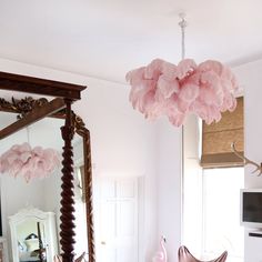 a pink chandelier hanging from the ceiling in a room with mirrors and furniture