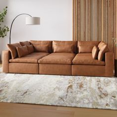 a brown couch sitting on top of a wooden floor next to a white and beige rug