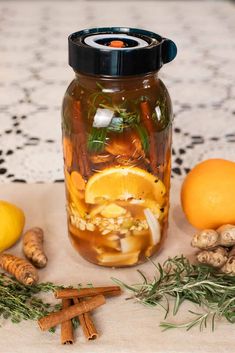 a jar filled with liquid sitting on top of a table next to lemons and ginger