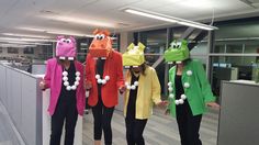 four people dressed up in costumes standing next to each other on a wooden floor with an office cubicle behind them