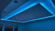 an empty room with blue lighting and stars on the ceiling, in front of a window