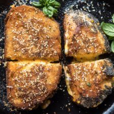 four pieces of bread sitting on top of a skillet with basil sprigs