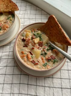 there is a bowl of soup and a sandwich on the table next to each other