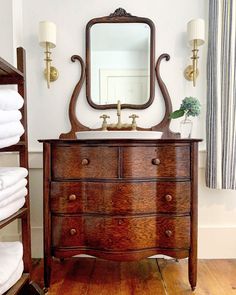 a bathroom with a dresser, mirror and towel rack in it's center area