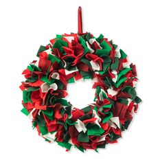 a red, green and white christmas wreath hanging on a string with a candle in the middle