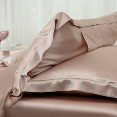 a bed with pink sheets and pillows on it