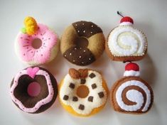 there are six different donuts on the white table top, each decorated with icing and sprinkles